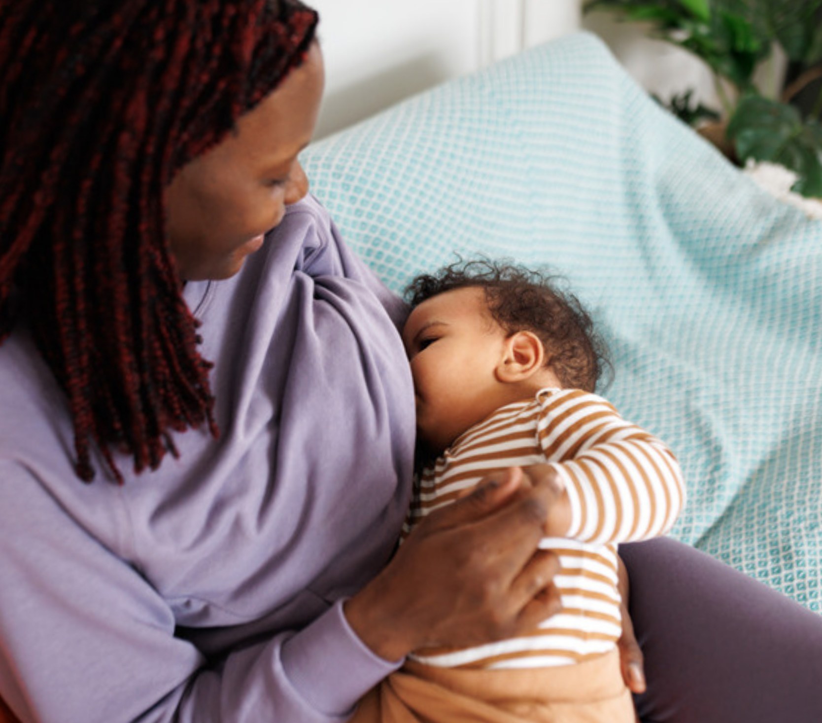 Mother breastfeeding her baby on a couch at home