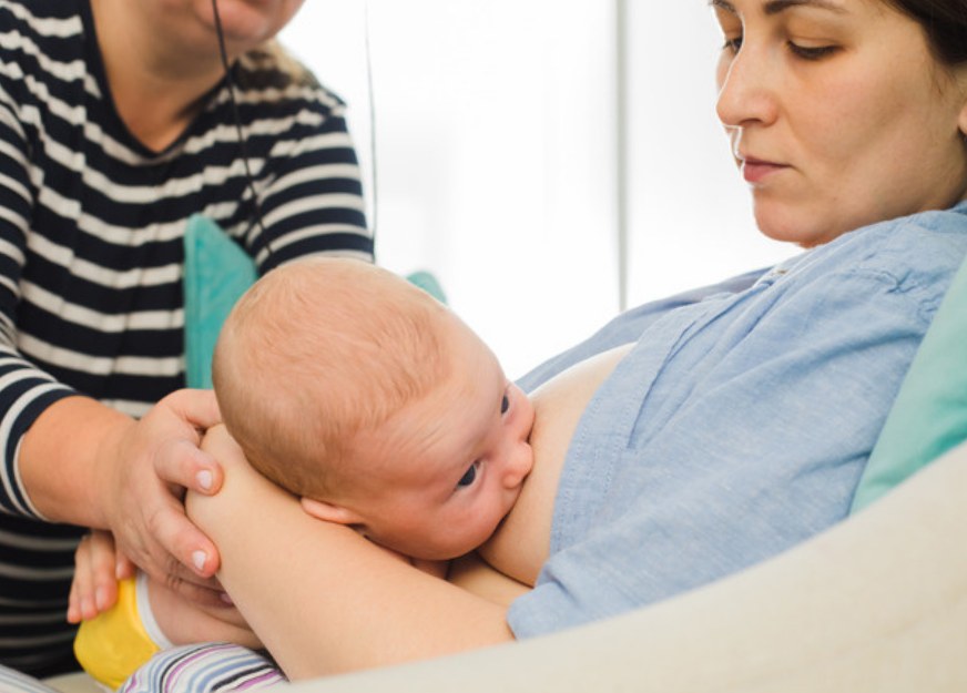 Lactation consultant supporting a mother while she breastfeeds