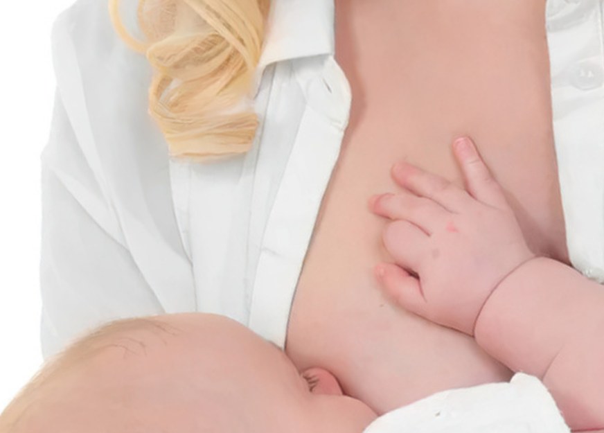 Close-up of a baby breastfeeding, one small hand resting on mother’s chest